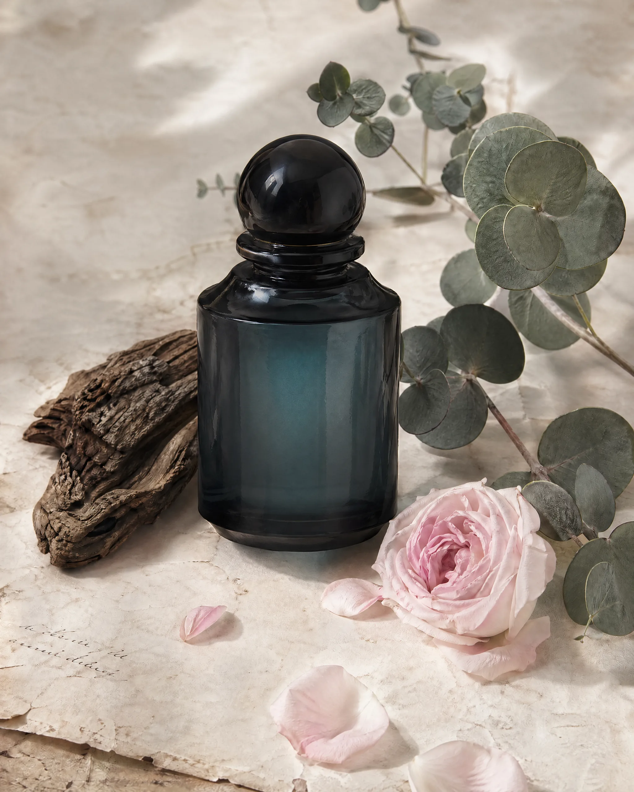 Flacon Abyssae teal sur parchemin avec fragment de bois cashmeran, eucalyptus, rose Damascena rose pâle